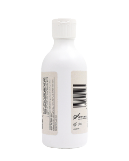 White bottle of Colloidal Oatmeal Lotion from the back, showing the back side of the label and barcode on a white background